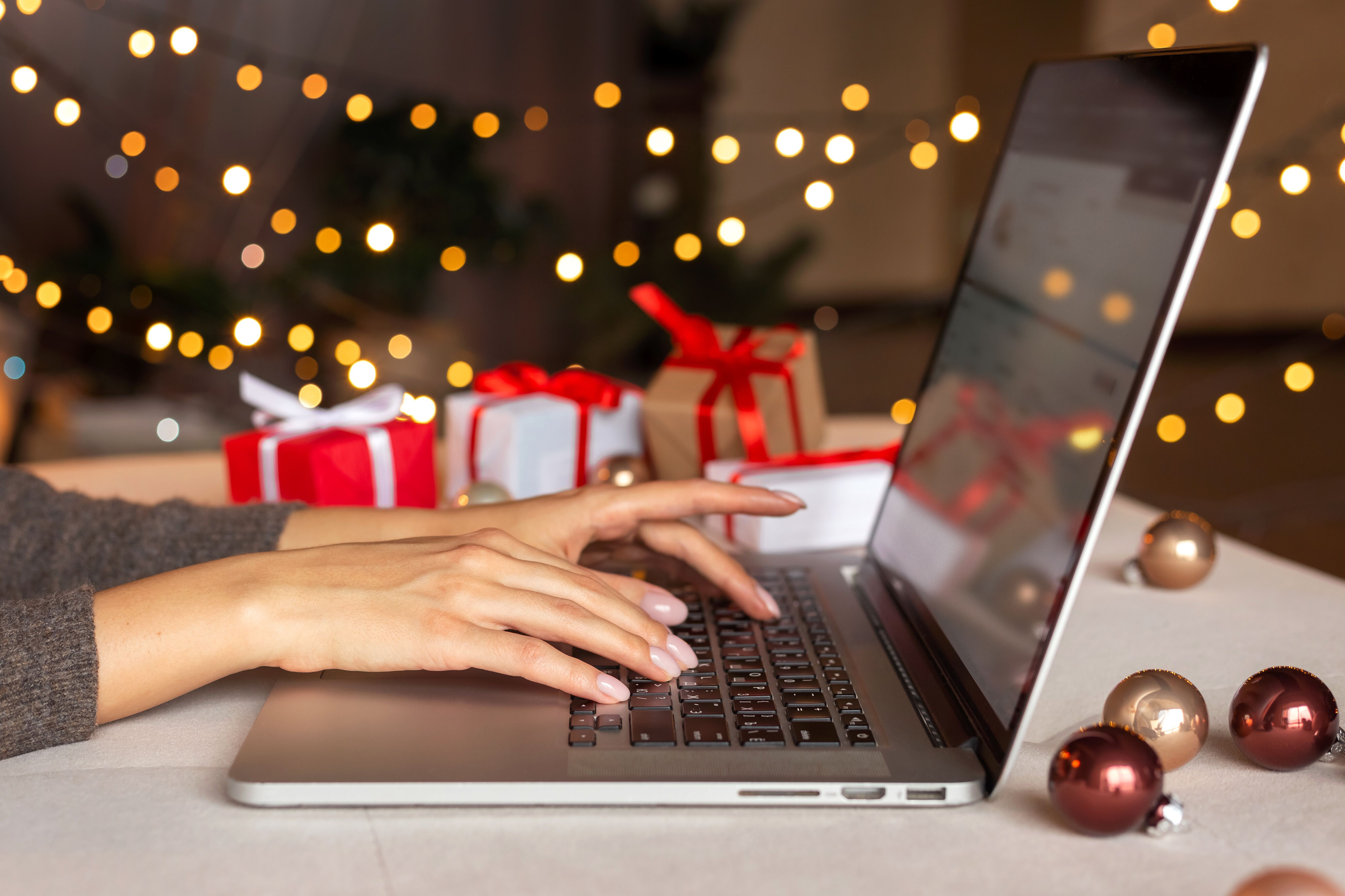 A person working at an office on a computer with holiday lights in the background - contact Custom Electrical Services  today to discuss electrical installation for your office!