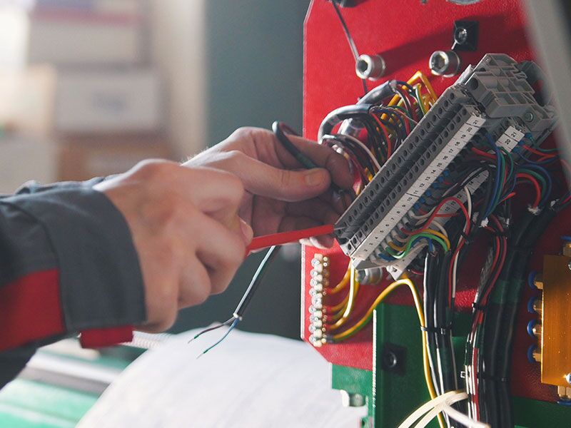 Custom Electrical Services  professional working on a bundle of colorful wires.