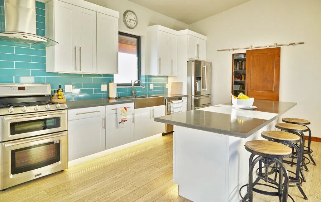 Inside a kitchen with a teal wall, white countertops, and newly installed floor lighting by Custom Electrical.